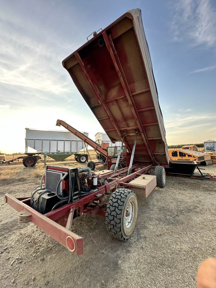 A bankout wagon with its bed raised at dusk, equipment yard behind it under a golden sky.
